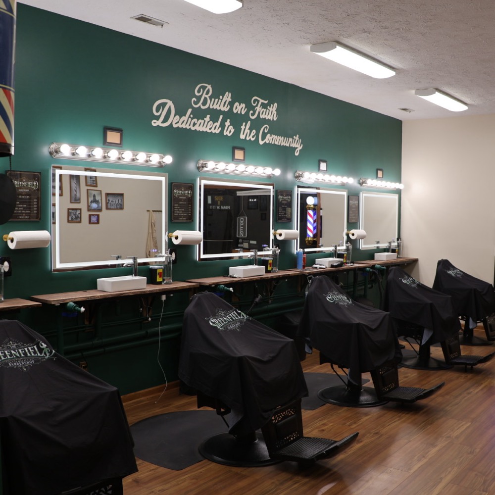Barber stations with branded capes over each chair under full lighting
